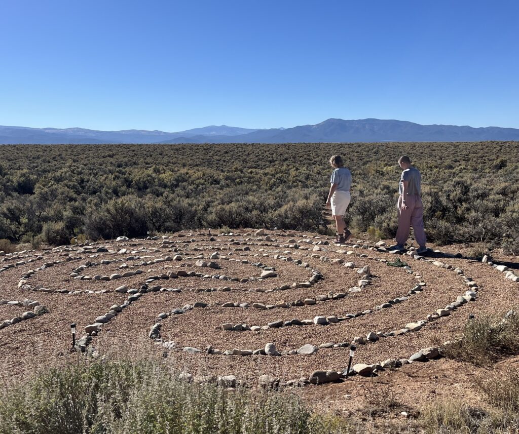 Two people with bowed heads are walking a labyrinth in the high desert.